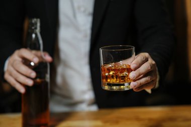 İş adamı içki deposunda elinde viski bardağıyla oturuyor.