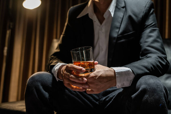 Businessman sitting Holding a Glass of Whiskey Drink Whiskey .