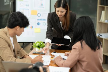 Asyalı iş hediyeleri beyaz tahtadaki grafiği açıklıyor. Danışmanlık, tartışma, bilgi alışverişi..