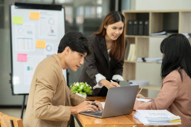 Asyalı iş hediyeleri beyaz tahtadaki grafiği açıklıyor. Danışmanlık, tartışma, bilgi alışverişi..