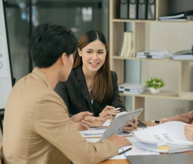Asyalı iş hediyeleri beyaz tahtadaki grafiği açıklıyor. Danışmanlık, tartışma, bilgi alışverişi..