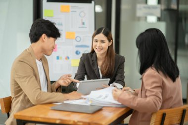 Asyalı iş hediyeleri beyaz tahtadaki grafiği açıklıyor. Danışmanlık, tartışma, bilgi alışverişi..