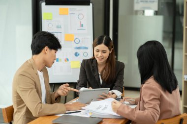 Asyalı iş hediyeleri beyaz tahtadaki grafiği açıklıyor. Danışmanlık, tartışma, bilgi alışverişi..