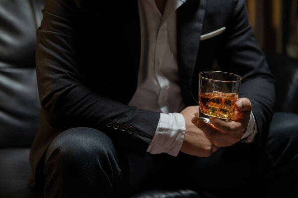 Бизнесмен, сидящий с бокалом виски в винном магазине