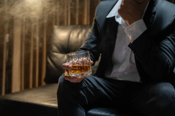 商人坐在酒库里 手里拿着一杯威士忌 喝威士忌 — 图库照片