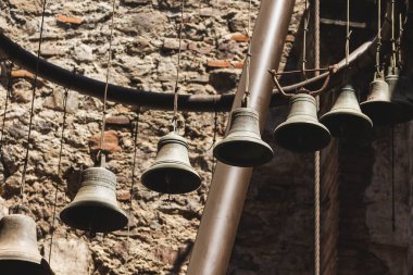 Antik bakır çan asılı, güneş ışığı var, insan yok. Melodik müzik enstrümanı.