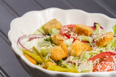 Taze ürünler ve refahı arttıran sulu nuggetlarla dolu renkli, besleyici bir yemek. Beyaz kasede İtalyan salatası. Marul, biber, biber, soğan, kızarmış ekmek ve doğranmış parmesan peyniri..
