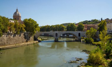 Roma 'nın tarihi köprüsünün panoramik görüntüsü güneşli bir günde İtalya' nın güzelliğini ve nehir manzarasındaki mimari cazibesini yansıtıyor. Roma 'da İtalya' da Vatikan 'da.
