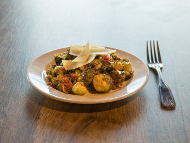 Çatal ve masa arkaplanı olan tabakta kızarmış brussel filizlerinin yüksek açısı. Yemek Sunumu İçin Mükemmel.