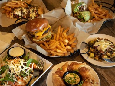 Masada, hamburger, sandviç, patates kızartması, et ve sebzeli Hero besin çeşitliliği sunuluyor..