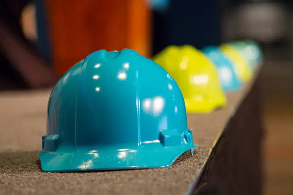 Horizontal photo of A blue hardhat with selective focus. Lined background on a flat end surface.