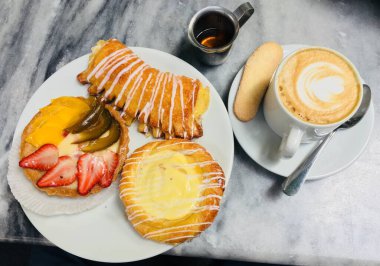 Üç tatlı hamur işi, sütlü kahve ve ballı tatlı manzaralı samimi bir ortam..