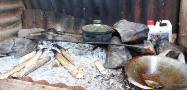 Üç ayaklı demir bir tencere, tuğla ateşi yerine odun ateşinin üzerinde. kül kömürü.