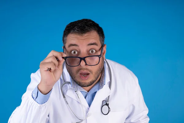 Close Médico Com Expressão Surpreendida Vestindo Óculos Fundo Azul Isolado — Fotografia de Stock