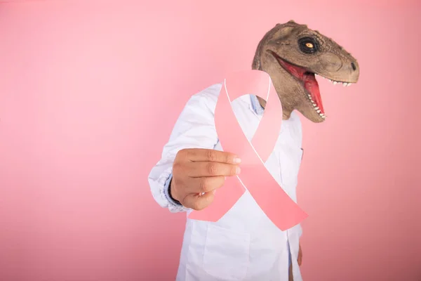 closeup of symbol of the fight against cancer with a dinosaur doctor behind it