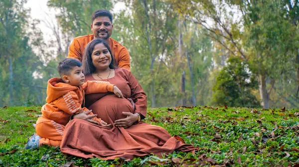 Kocası ve çocuğuyla birlikte genç hamile bir kadın, dışarıda eğleniyor, Hint aile kavramı.