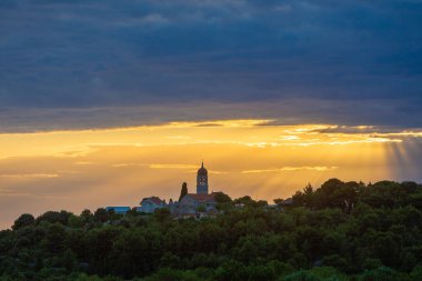 Sunset with dark clouds with a church on the top of the hill, Brac Island, Croatia