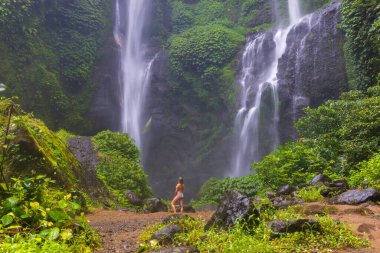 Endonezya 'daki Bali Adası' nda Sekumpul Şelalesi önünde mayo giymiş genç bir kadın.