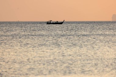 Sunset on Andaman sea with a lone longboat in the background, Thailand clipart