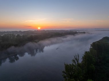 Sabah sisi ve yükselen güneşin doğal Drava Nehri üzerindeki hava manzarası ve orman taşkın ovası.