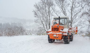 This backhoe was parked on the side of the road. It is to be used to shovel snow that falls on the road blocking traffic during a snowstorm.