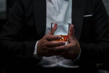 Yakından bir bardak viski tutan iş adamları.