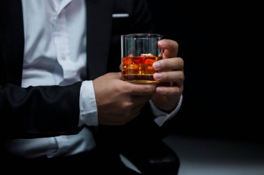 Yakından bir bardak viski tutan iş adamları.