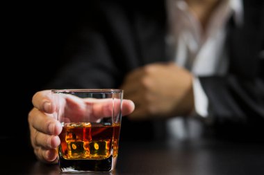 Yakından bir bardak viski tutan iş adamları.