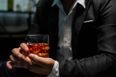 Yakından bir bardak viski tutan iş adamları.