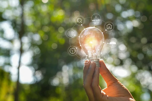 stock image hand holding light bulb against nature, icons energy sources for renewable,