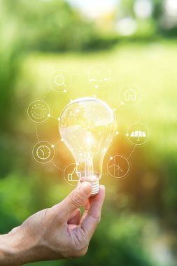 Doğaya karşı el ele tutuşan ampul, yenilenebilir enerji kaynakları için simgeler,