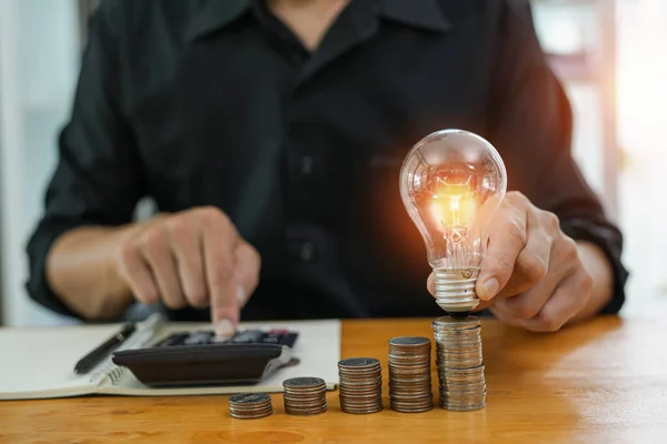 stock image Business man holding light bulb on the Green background nature and writing on note book it for financial