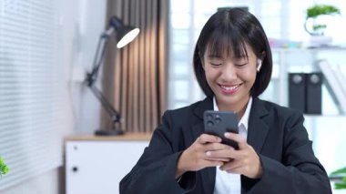 Ofiste akıllı telefon kullanan bir iş kadını başarılı bir kadın yöneticiyle mesajlaşıyor..