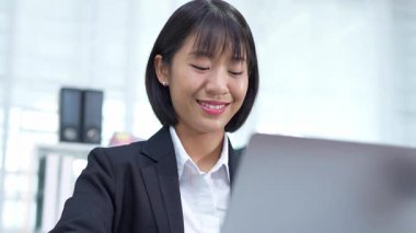 Masada çalışan Asyalı iş kadını dizüstü bilgisayar ve not defteri kullanarak müşteri ya da ofis binasıyla konuşuyor, yavaş çekim görüntüleri