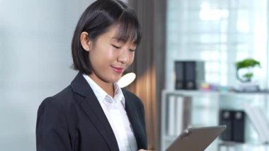 Masada çalışan Asyalı iş kadını dizüstü bilgisayar ve not defteri kullanarak müşteri ya da ofis binasıyla konuşuyor, yavaş çekim görüntüleri