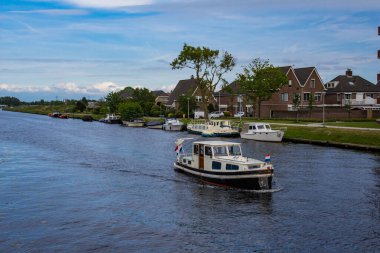 Bulutlu bir yaz gününde Hollanda 'da bir kanalda eğlence teknesi. Su..