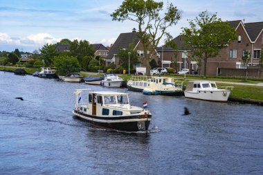 Bulutlu bir yaz gününde Hollanda 'da bir kanalda eğlence teknesi. Su..