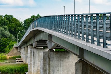 Yaz bulutlu bir günde yeşil ağaçların arasında nehir üzerinde bir köprü. Nehir.