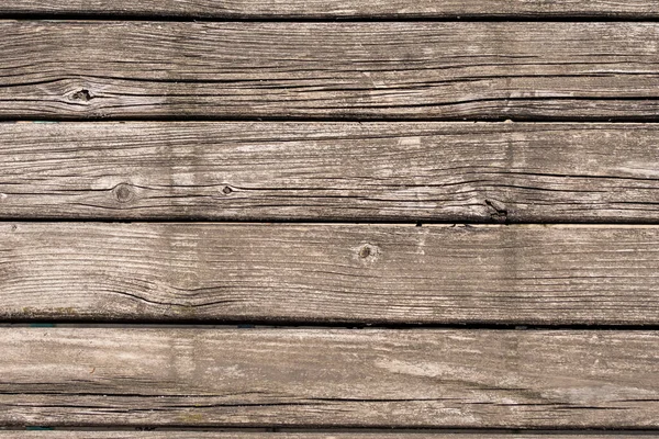 Old faded boards on a deck or outdoor table in the midday sun in close-up.