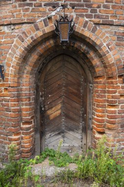 Kapının üzerinde asılı bir fener olan tarihi bir tuğla binaya giriş. Duvar.