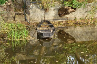 A boat moored to the river bank in the reeds on a sunny, calm day.