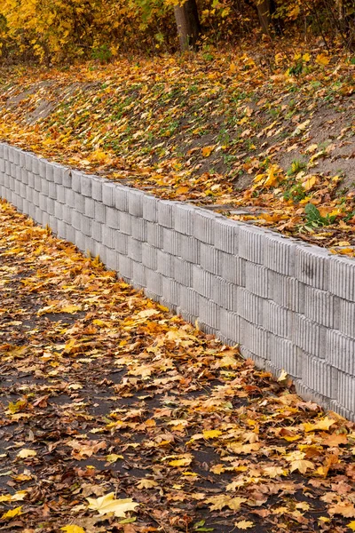 Beton elementlerden yapılmış bir istinat duvarı yolu ve kaldırımı yokuş aşağı kaymaktan korur..
