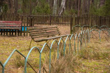 İhmal edilmiş ve terk edilmiş bir tatil köyünde eski bir bank ve metal bir çit..