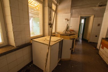 Kullanıcılardan kalan çöp, mobilya ve bardaklarla dolu terk edilmiş bir sanayi mutfağının içi.. 