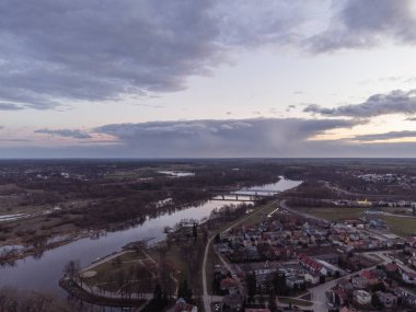 Gün batımı ve fırtına bulutları bir bahar günü nehir ve şehir üzerinde.