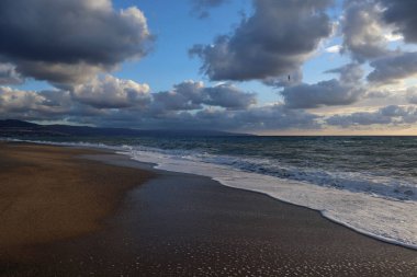 Denizin üzerinde fırtına bulutları, dalgalar ve kumlar Calabria, İtalya sahillerinde.