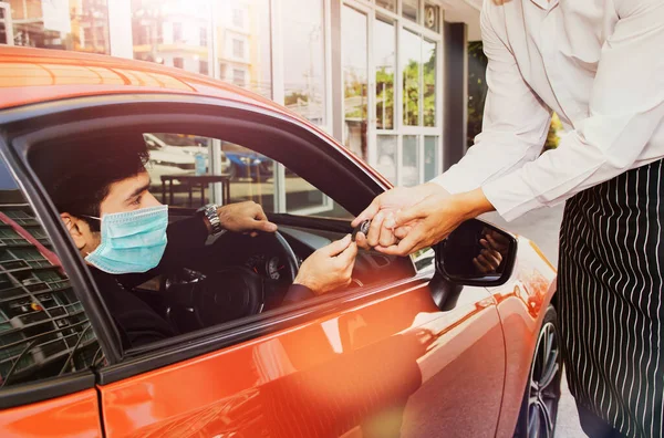 stock image Handsome business man, private driver in a mask, gives the hotel attendant a hotspot key to serve and treat customers entering the hotel to make a good impression : Great concierge service to customer