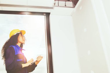 Kask takan kadın işçi, güvenlik sistemini büyük bir ilgi ve şevkle uygulamak için binanın inşaat ve iç yenileme alanındaki ofis tavan yapısını inceliyor..