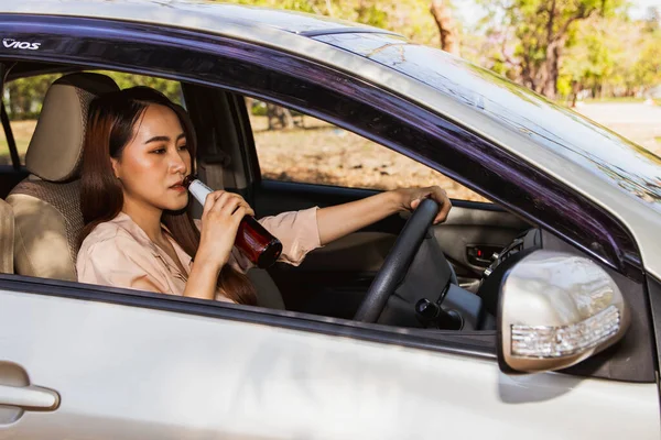 Asian woman drinking beer and alcoholic beverages while driving : Irresponsible women do not respect the law drink and drive risking accidents : Concept of not drinking, not driving for safety.