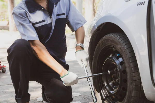 stock image Male mechanic provides emergency assistance replaces accidental tires flattened tires during travel and checks the safety of tightening wheel nut : Banner